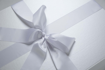 Die Brautkleidbox Pearly Stripes wird mit einem weißen Satinband gebunden.
