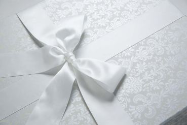 Die Brautkleidbox Tapestry Silver wird mit einem weißen Satinband gebunden.