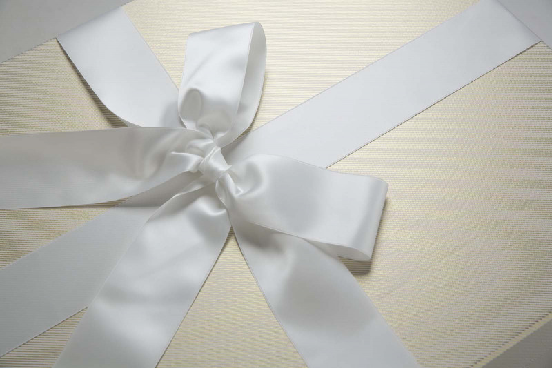 Die Brautkleidbox Stripes White & Gold wird mit einem weißen Satinband gebunden.